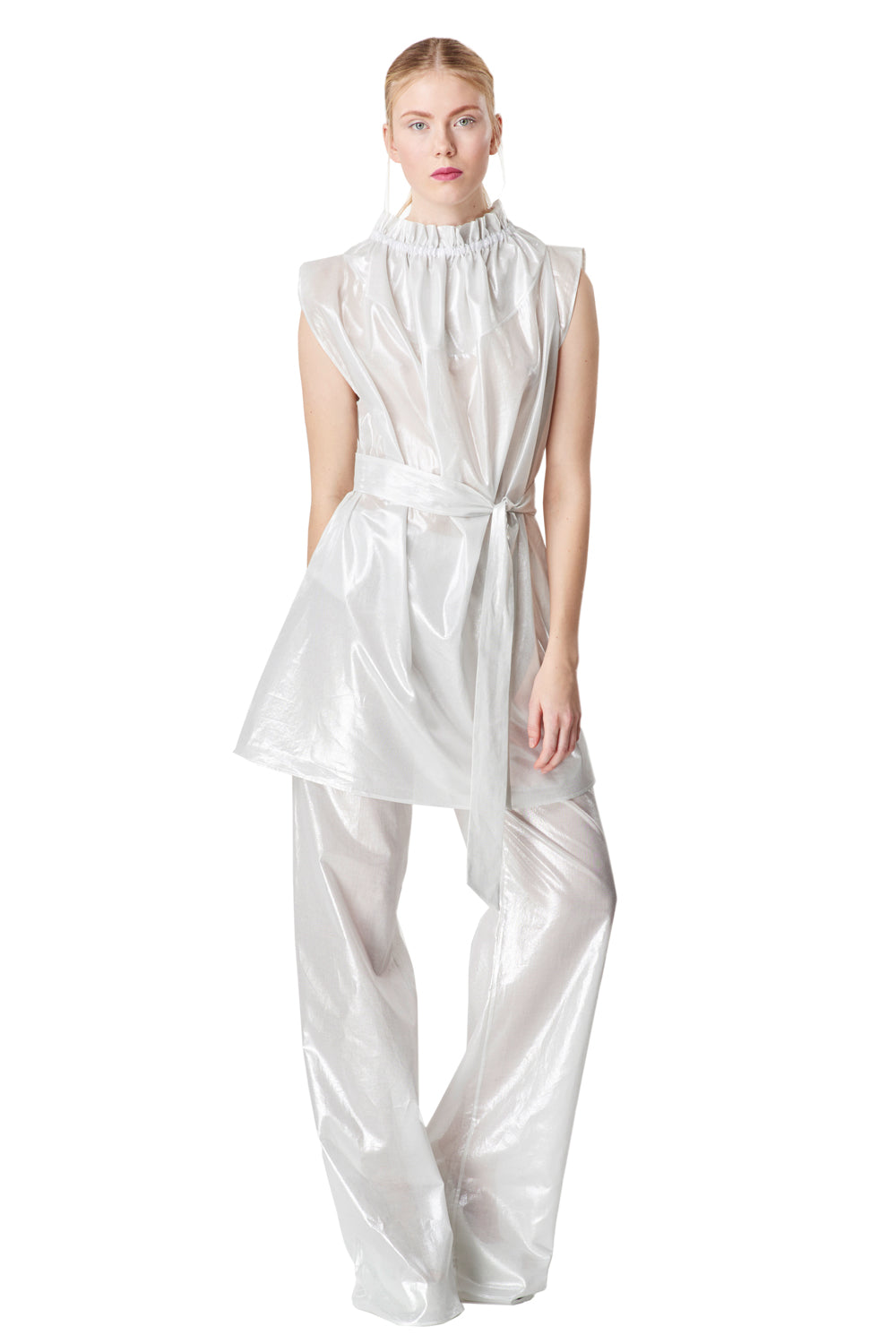 A model in a white metallic overall stands confidently, highlighting the relaxed elegance of her outfit. 