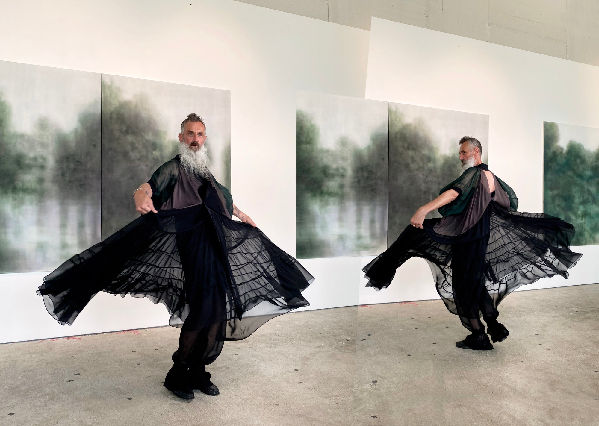 A man with a beard dressed in an elegant black silk cape, showcasing its flowing fabric in two different poses in an art gallery.