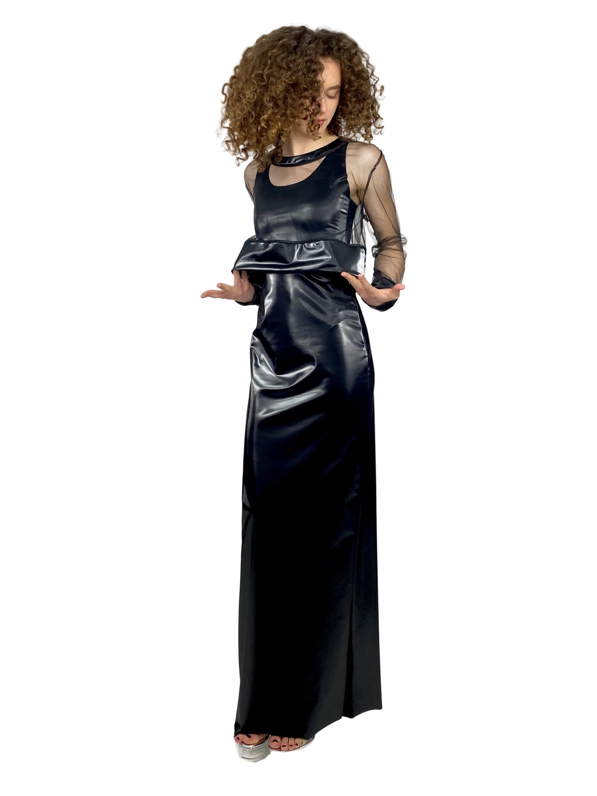 Woman wearing a black evening gown with sheer sleeves on a white background