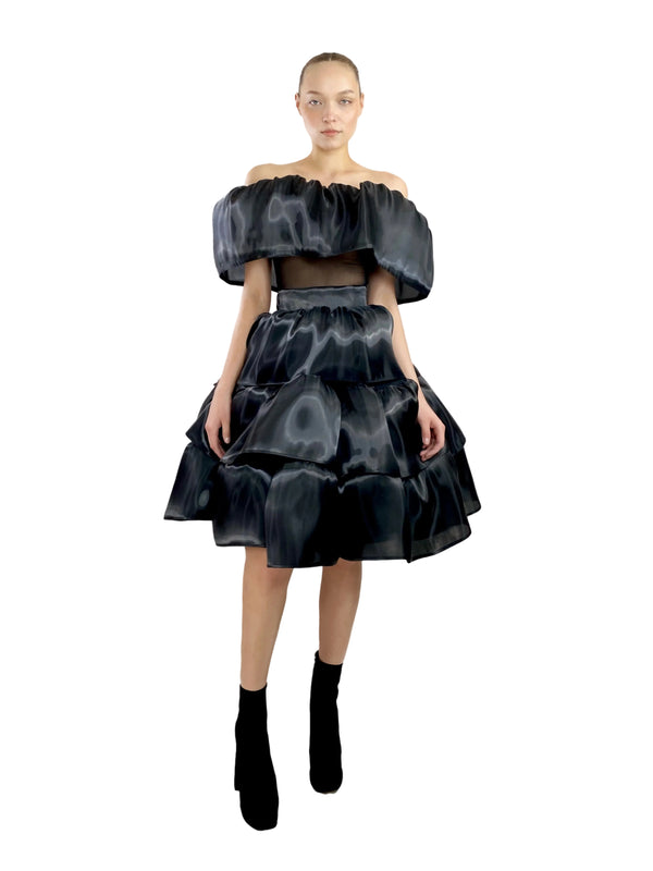 Model wearing a black patterned outfit on a white background