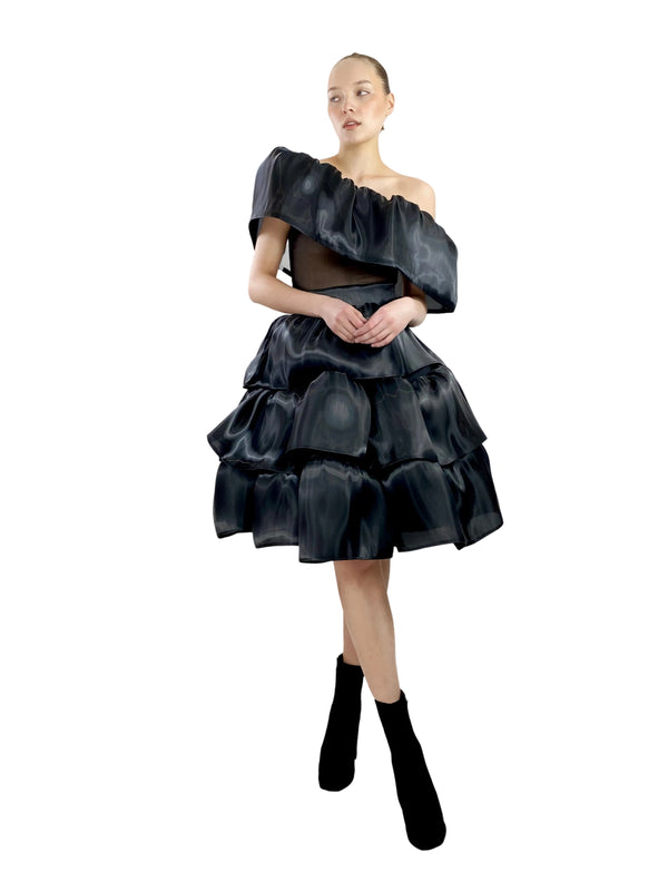 Woman wearing a black, layered dress on a white background