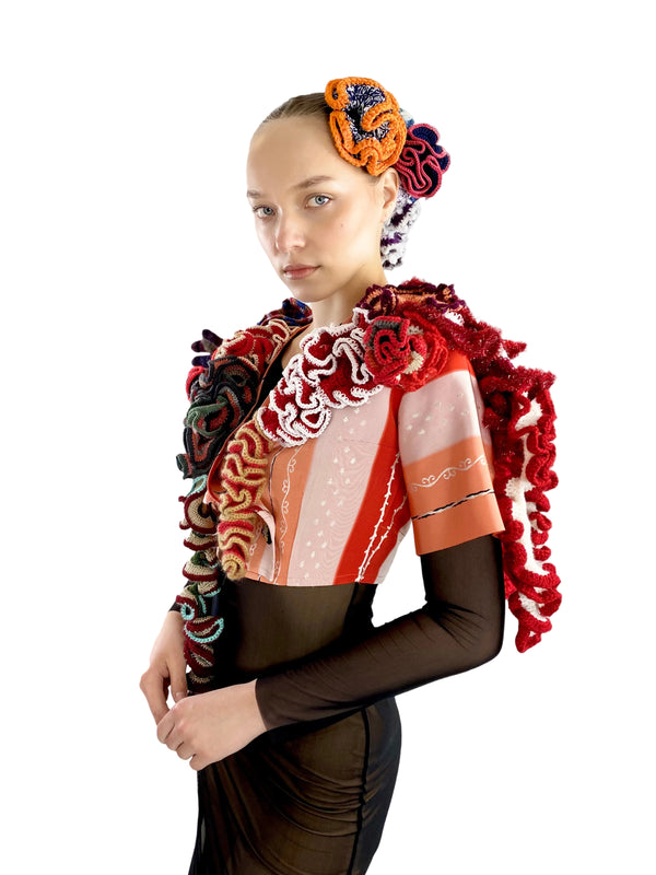 Model wearing a colorful outfit with intricate patterns on a white background
