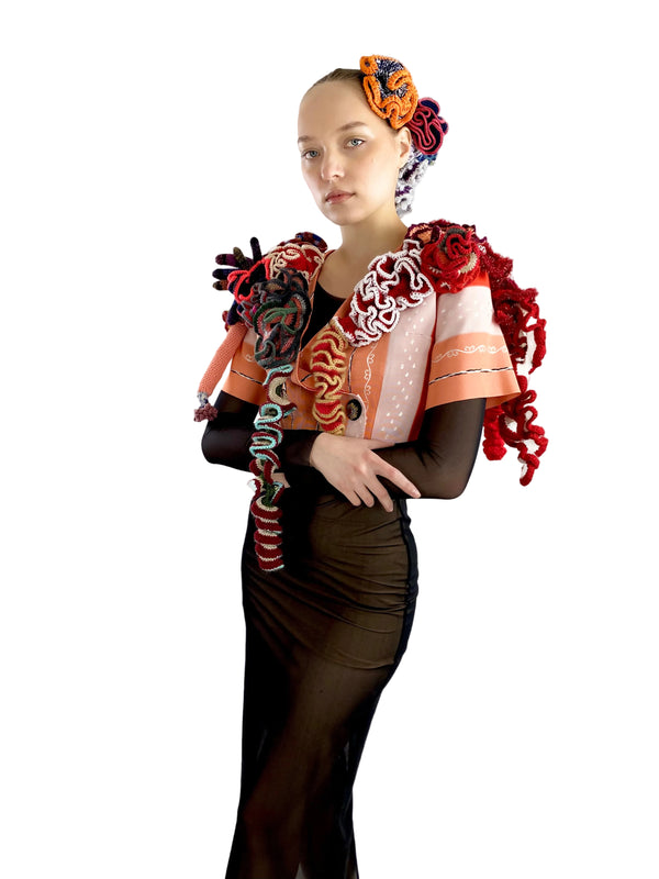 Person wearing a colorful, textured garment with floral headpiece on a white background