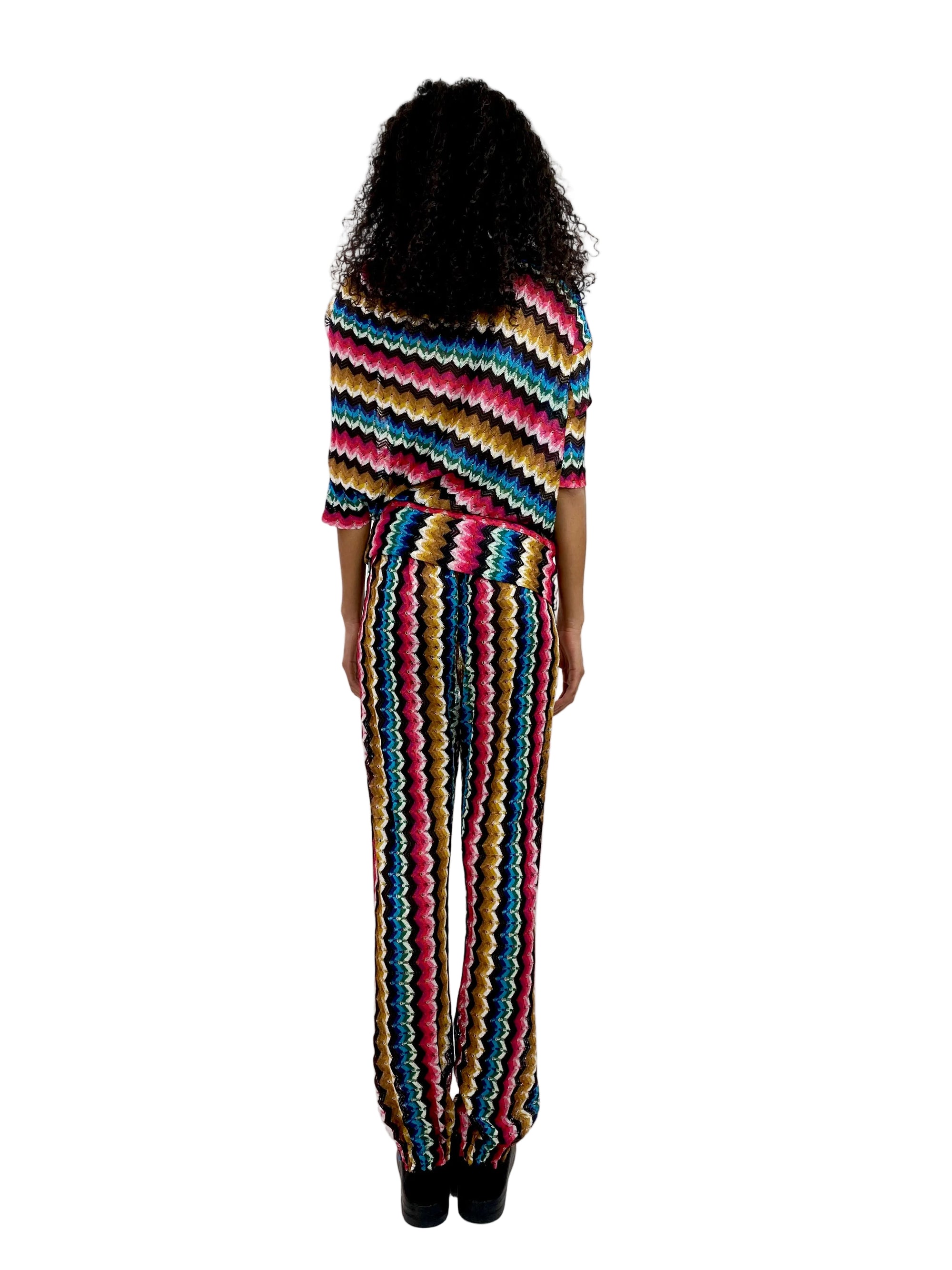 Person wearing a colorful striped poncho and pants on a white background
