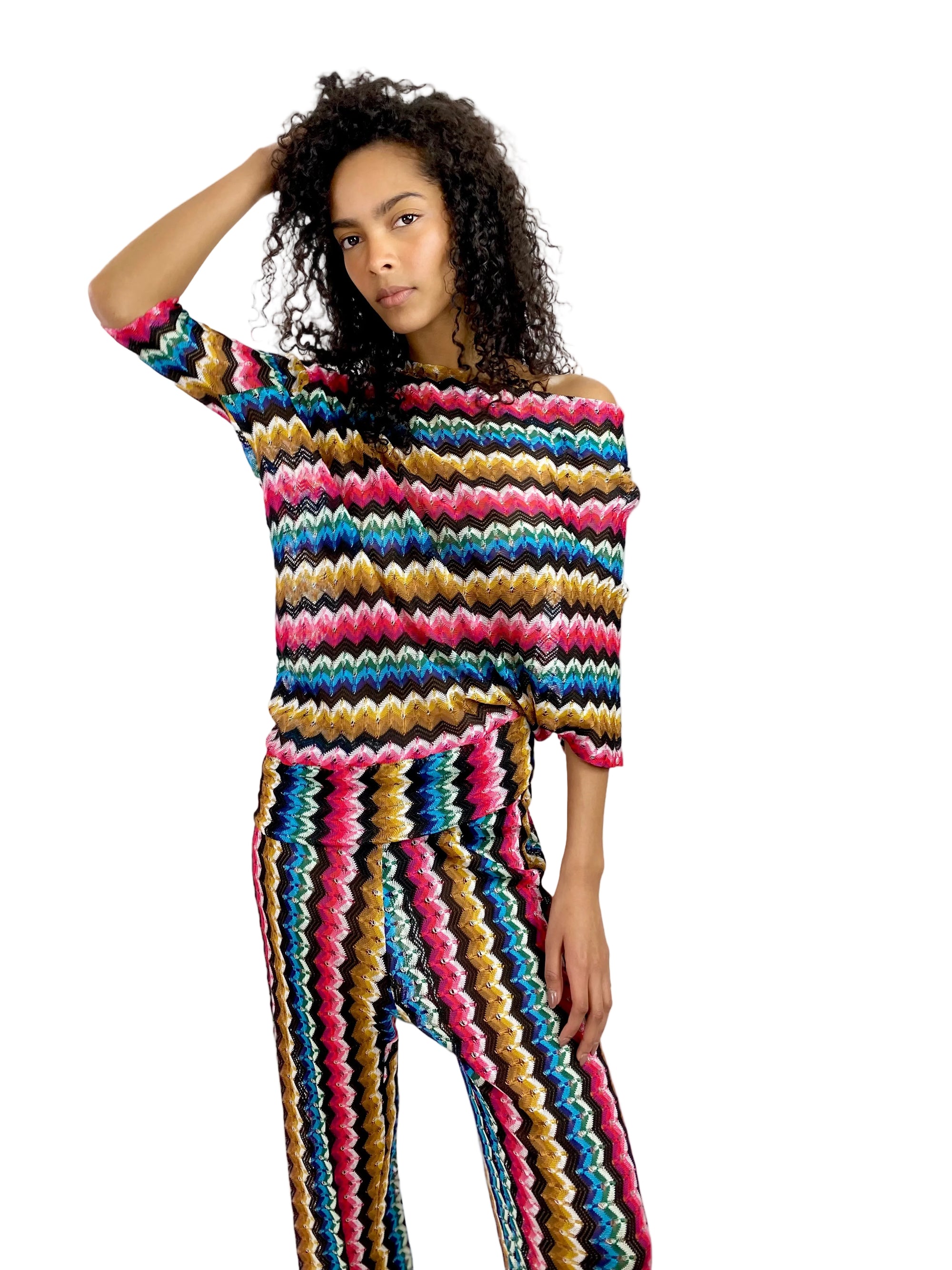 Woman wearing a colorful striped sweater and pants on a white background