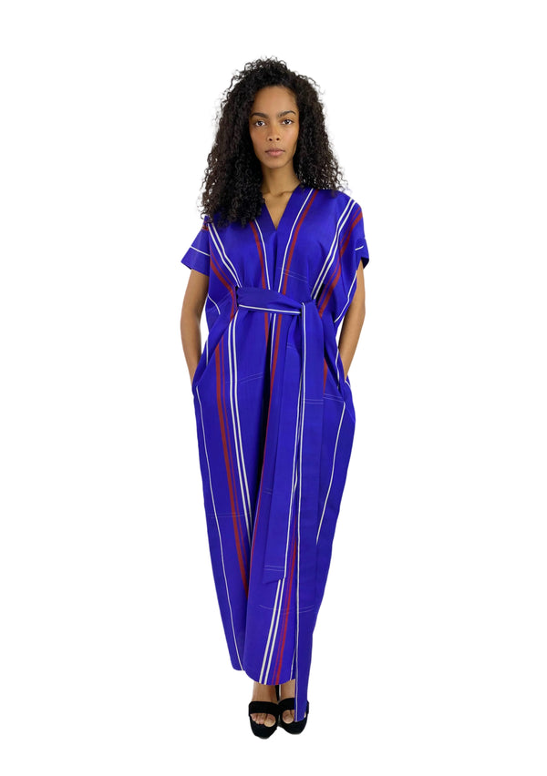 Woman wearing a blue jumpsuit with white and red stripes on a white background