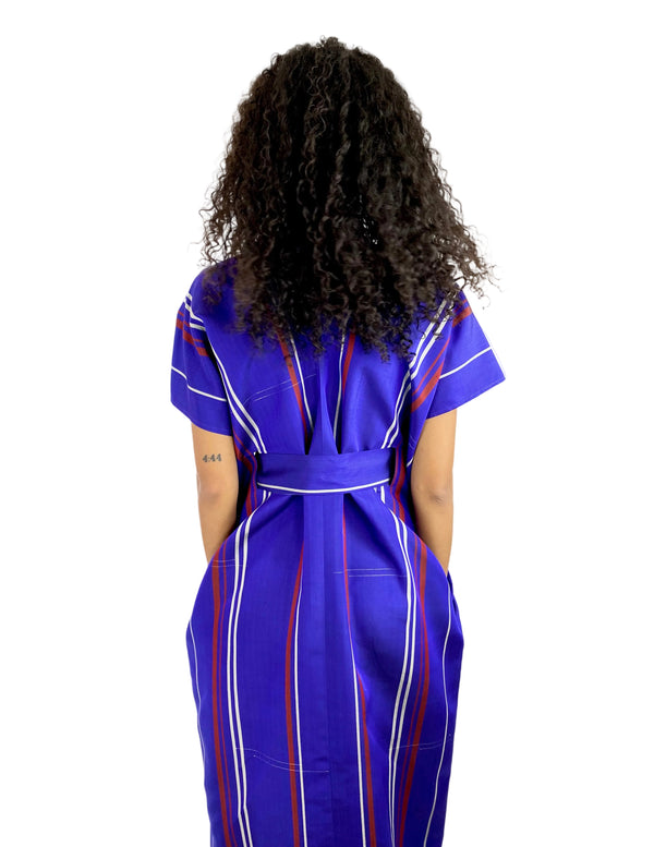 Person wearing a blue dress with red and white stripes from behind on a white background