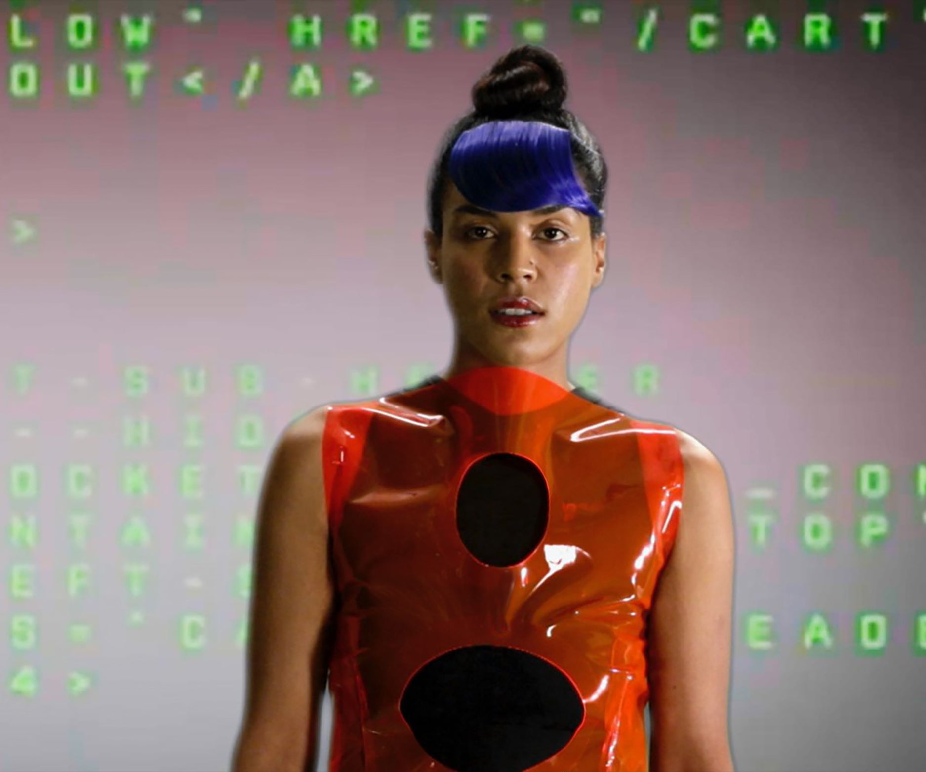 A woman wearing an orange plastic dress and sporting vibrant blue hair stands confidently against a virtual computer screen.